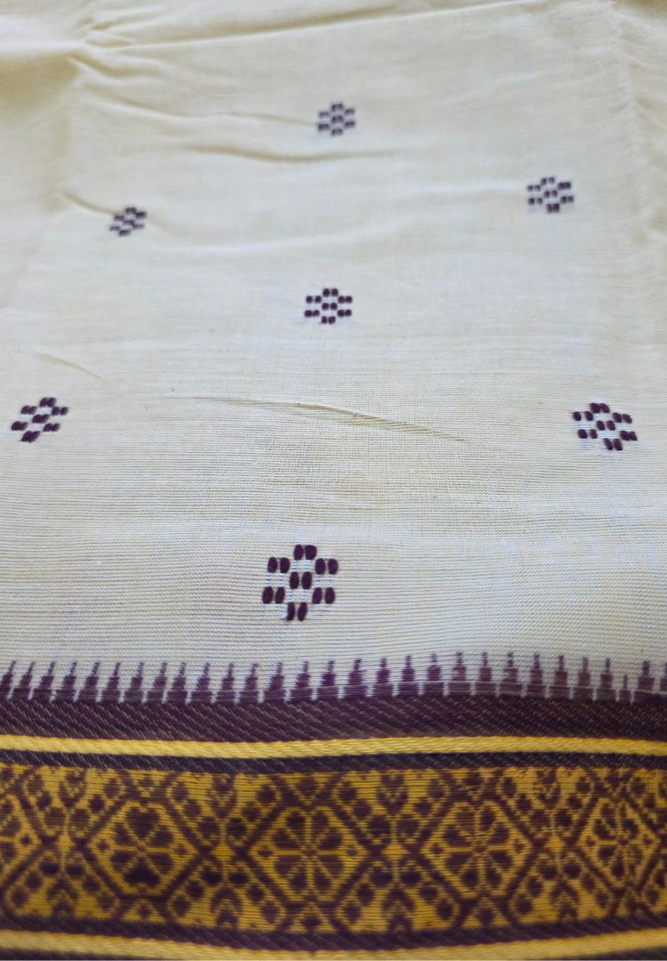 Close-up of buttis and brown woven border on a beige Dhaniakhali cotton saree