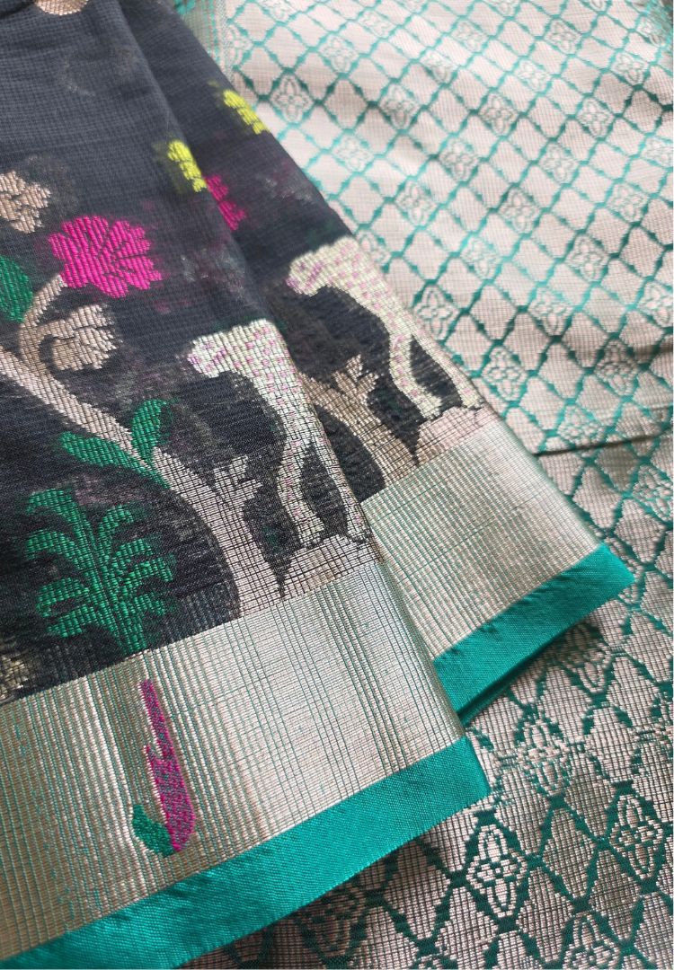 Woven deer and tree motifs above the teal zari border of a black Kota silk saree