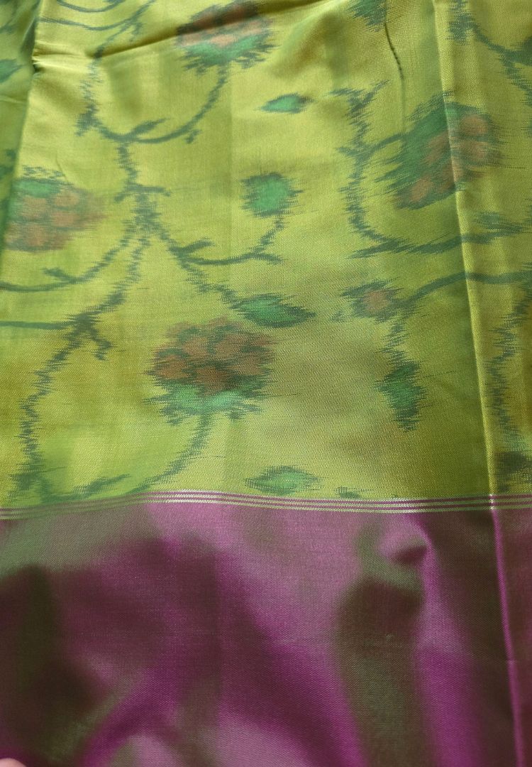 Close-up of Ikkat floral weaving on a parrot green semi katan silk saree